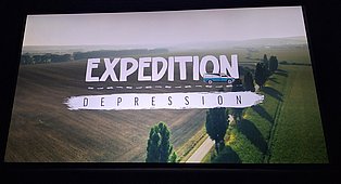 Titelbild des Filmes Expedition Depression, Eine Landstraße umgeben von Feldern von oben und der Titel des Films.