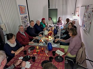 10 Selbsthilfe-Aktive sitzen um einen adventlich geschmückten Kaffee-Tisch